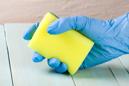 Hand in rubber glove with sponge on a wooden backgroundの写真素材