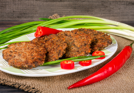 liver pancakes or cutlets with chili pepper and green onions on a wooden background