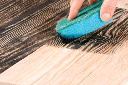 painting wooden board with a sponge in black colorの写真素材