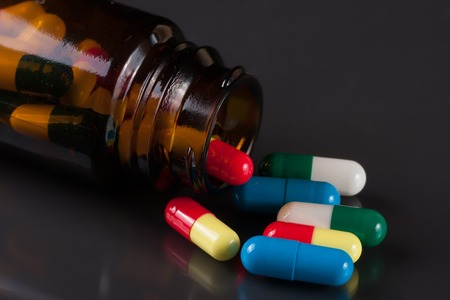 colorful pills in a glass bottle on a dark backgroundの写真素材
