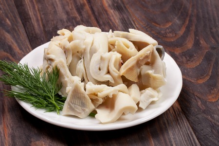 sliced squid on a plate on a dark wooden background