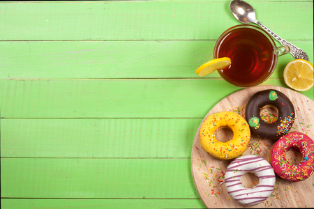 glazed donuts with a cup of tea on a green wooden background with copy space for your text. Top viewの写真素材