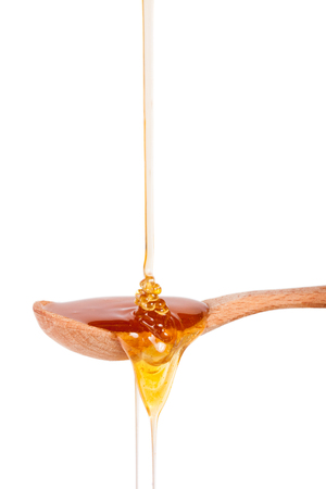 Honey in a wooden spoon isolated on a white backgroundの写真素材