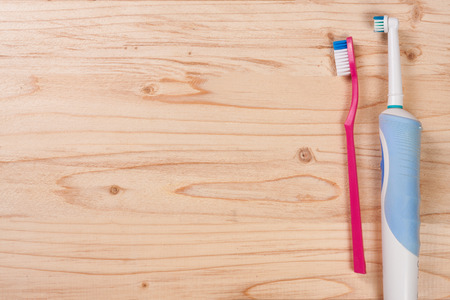 electric and manual toothbrushes on the light wooden background with copy space for your text. Top viewの写真素材