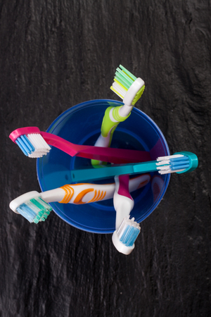 Toothbrushes in a blue plastic glass on black stone backgroundの写真素材