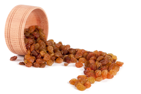 raisins in a wooden bowl isolated on white backgroundの写真素材