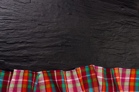 Red checkered tablecloth on a dark stone background with copy space for your text. Top view