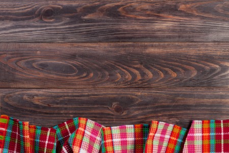 Red checkered tablecloth on a dark wooden table with copy space for text. Top viewの写真素材