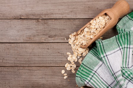 Oat flakes in a wooden scoop on old wooden background with copy space for your text. Top viewの写真素材