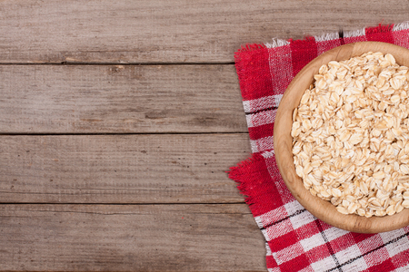 Oat flakes in a wooden bowl on old wooden background with copy space for your text. Top viewの写真素材