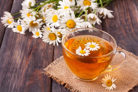 Herbal tea with fresh chamomile flowers on black wooden backgroundの写真素材
