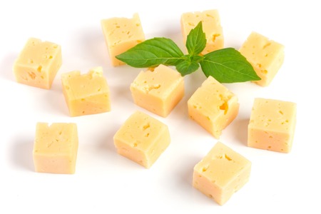 cheese cut into cubes with basil leaves isolated on white backgroundの写真素材