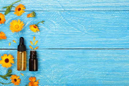 aromatherapy essential oil with marigold flowers on blue background with copy space for your text. Top viewの写真素材