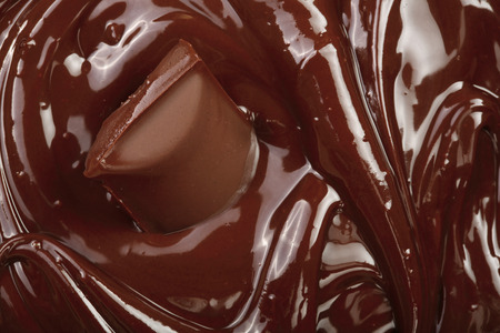 Melted chocolate and pieces of chocolate bar as a background closeup.