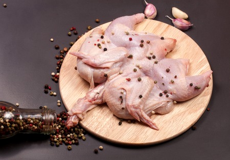Raw chicken carcass with peppercorns on a darkの写真素材