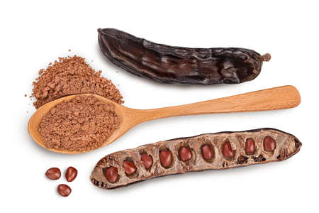 Carob pod and powder in wooden spoon isolated on white background with clipping path. Top view. Flat...