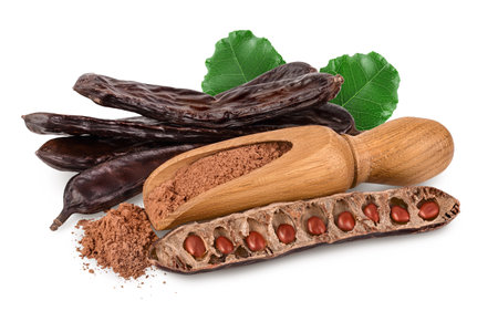 Carob pod and powder in wooden scoop isolated on white background with full depth of field.の写真素材