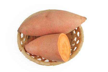 Sweet potato in a wicker basket isolated on white background. Top view. Flat layの写真素材