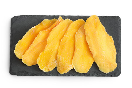 dried mango on a black stone board isolated on white background. Top view. Flat layの写真素材