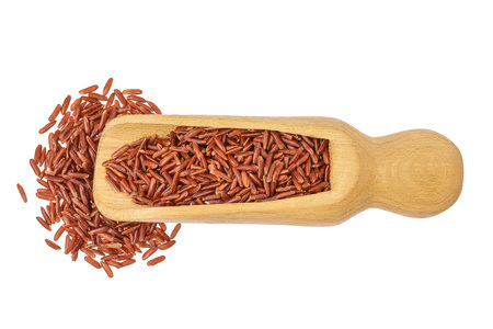 red rice in a wooden scoop isolated on white background. Top view. Flat layの写真素材