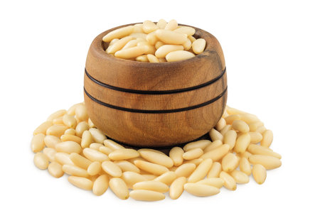 Shelled European pine nuts in wooden bowl isolated on white background with full depth of fieldの写真素材