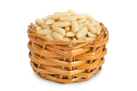 Shelled European pine nuts in a wicker basket isolated on white background with full depth of fieldの写真素材