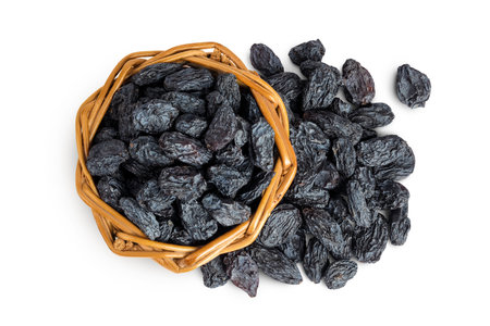 black raisins in wicker basket isolated on white background. Top view. Flat layの写真素材