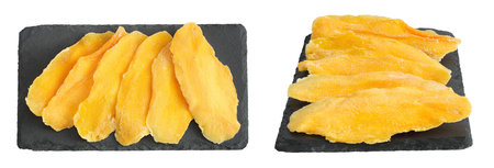 dried mango on a black stone board isolated on white background. Top view. Flat layの写真素材