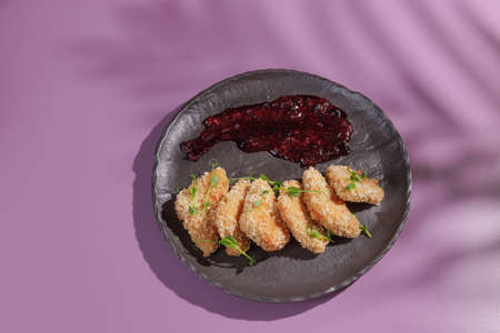 baked eggplant with white sauce and lettuce on green background with shadow from palm tree, top viewの写真素材