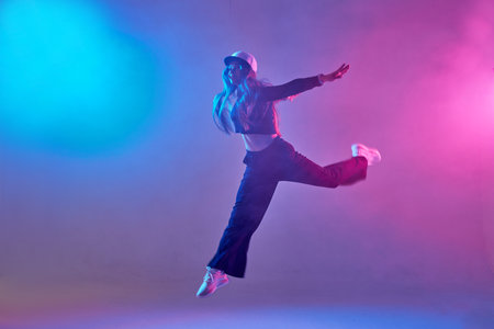 a girl in dark clothes dances on a neon background in smoke, modern danceの写真素材