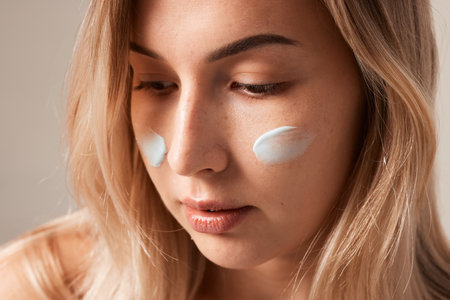 Close up beauty portrait laughing beautiful half naked woman applying face cream make up health spa fresh skinの写真素材