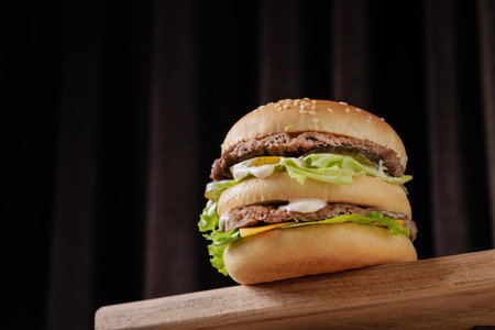 perfect tasty big double burger on wooden table on brown background, bottom viewの写真素材