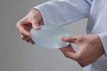 Doctor surgeon holding breast silicone implant in clinic. Breast enlargement surgery conceptの写真素材
