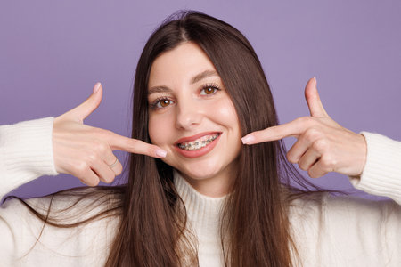 portrait of a girl with braces, woman happy with braces shows ok sign