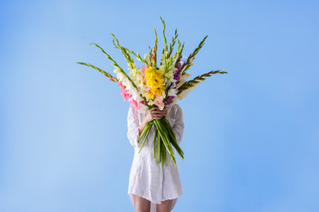 girl with gladioli flowers in white clothes on a white backgroundの写真素材