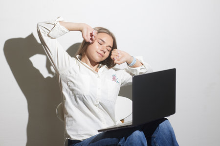 tired girl at a table with a laptop on a white background