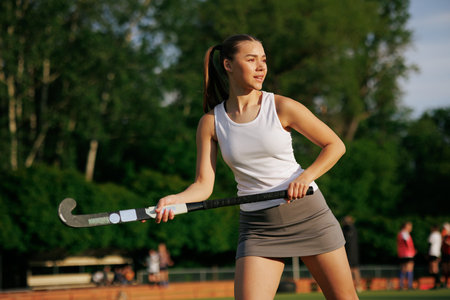 girl hockey player plays field hockey on a sunny day, female hockey player hits the ball with a...