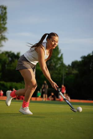 girl hockey player plays field hockey on a sunny day, female hockey player hits the ball with a stick, field hockey conceptの写真素材
