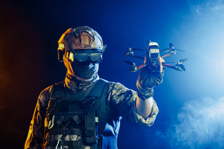 Soldier in gear holds drone against a red and blue smoky background, conveying intensity and military actionの写真素材