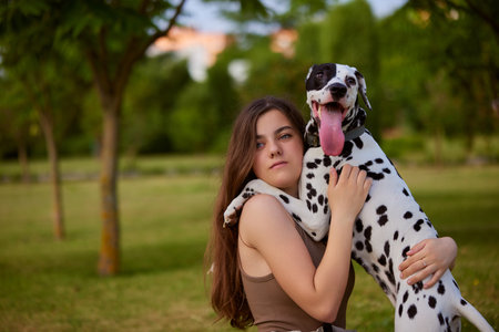 a young girl plays with a Dalmatian in the park. dog care concept, love for animals conceptの写真素材