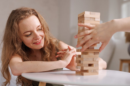 two women playing a board game made of wooden blocks at home, excitement and relaxation, mind development concept, hand motor skills,の写真素材