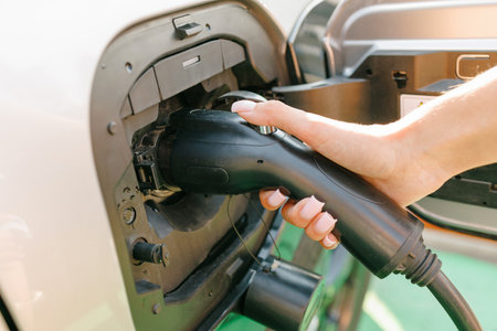 a girl charges her electric car at a charging station, Environmentally friendly energy sources,...