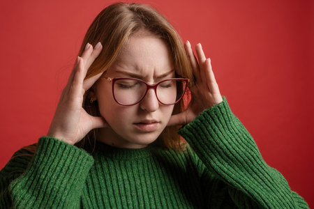 severe headache, brain spasm, portrait of a girl with glasses squeezing her hands to her templesの写真素材