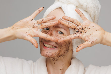 Woman enjoying facial skin care, applying black coffee face scrub, concept of rejuvenation and facial skin careの写真素材