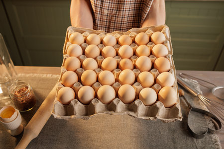 A man holds a large egg carton, with 30 eggs visible in it. In the background is a kitchen setting...