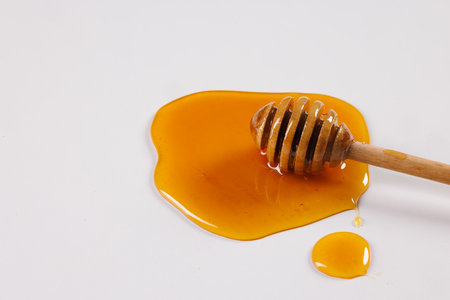 honey spoon with spilled honey on white background, top view, honey benefits conceptの写真素材