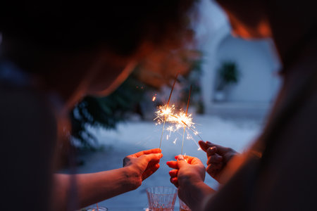 girls celebrating sparklers in hands close up in evening, holiday conceptの写真素材