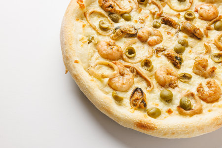Close-up of a seafood pizza with shrimp, olives, and onions on a white background.の写真素材