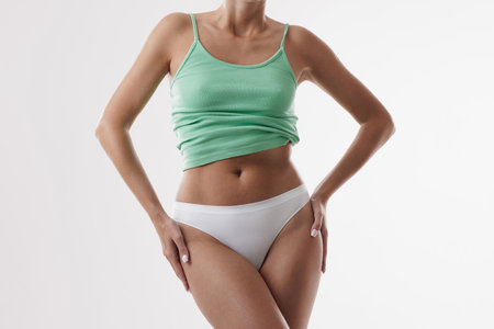 portrait of woman with perfect figure in white panties and green top on isolated white background, healthy female body conceptの写真素材