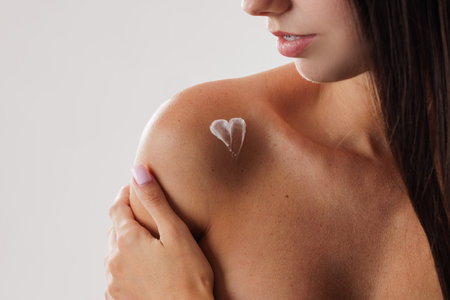 Close up of woman's shoulder with heart shaped cream or lotion applied on skin, body care conceptの写真素材